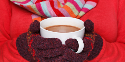 Cold woman holds hot chocolate with gloves